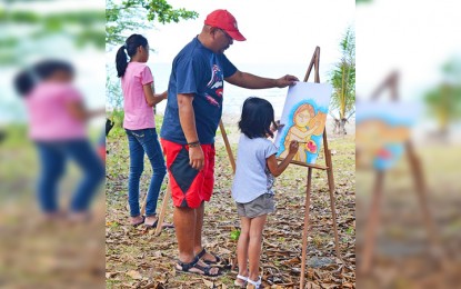 <p>Bohemian coffee artist Renato Tuzon teaches a young resident of Amoingon, Marinduque the basics of oil pastel painting.<em> (Photo courtesy of Toby Jamilla)</em></p>