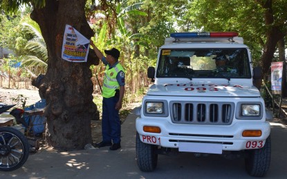 <p><strong>OPERATION BAKLAS</strong>. A police in Pinili town removes a campaign material posted on a tree in Pinili, Ilocos Norte on Friday (May11,2018).<em> (Photo courtesy of Pinili PNP)</em></p>