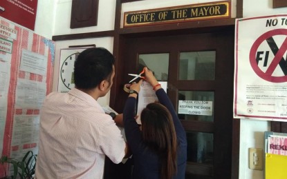 <p><strong>DISMISSAL ORDER POSTED.</strong> Employees of the Department of Interior and Local Government post the dismissal order against Paoay Mayor Jessie Galano and municipal administrator Bruno Dumlao on the door of Office of the Mayor on Thursday afternoon (June15, 2018). <em>(Photo by Leilani Adriano) </em></p>