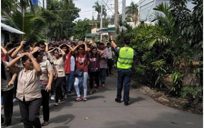 <p>EARTHQUAKE DRILL. A Laguna police officer directs teachers, students, townsfolk and “earthquake victims” to “safety,” as he ensures traffic management as part of vital police operation - in one of the scenarios and simulated drills in schools and communities for the 2nd Quarter Nationwide Simultaneous Drill (NSED) 2018 on June 21, 2018.<em> (Photo courtesy of LPPO-PIO)</em></p>