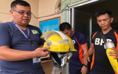 <p style="text-align: justify;"><strong>NEW FIREFIGHTING PROTECTION EQUIPMENT. </strong>Superintendent Catalino Ramos (left), Bureau of Fire Protection (BFP)-Palawan provincial director, shows a sample of the new helmets that his office will issue to firefighters in various towns of the province. <em>(Photo by Celeste Anna R. Formoso)</em></p>