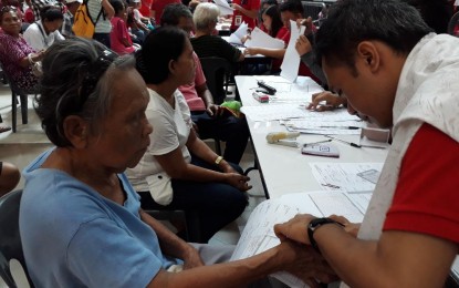 <p>A personnel of the Department of Social Welfare and Development (DSWD) -11 guides Fidela Plasabas to put her thumb mark to her filled-out form for the Unconditional Cash Transfer cash grant during the launching program on Wednesday at SM Davao Annex. <em><strong>Lilian C. Mellejor/PNA</strong></em></p>