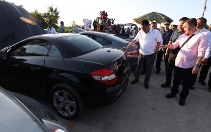 <p>SMUGGLED LUXURY CARS. President Rodrigo R. Duterte inspects one of the contraband luxury vehicles before they were subjected to condemnation and public destruction at Port Irene in Sta. Ana, Cagayan on July 30, 2018. A total of 68 contraband luxury vehicles worth over PHP277 million and eight contraband luxury motorbikes worth over PHP19 million were destroyed as part of the President's campaign against smuggling and corruption in the government.<em> (Robinson Niñal Jr./Presidential Photo) </em></p>