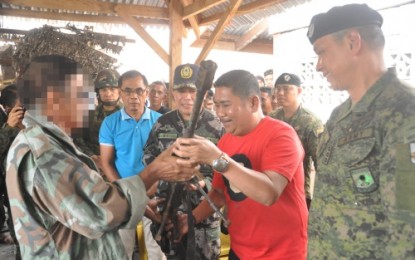 <p><strong>BIFF SURRENDER.</strong> Maguindanao 2nd District Representative Zajid Mangudadatu (red shirt) holds a rifle from one of the BIFF surrenderers as Colonel Robert Dauz, 1st Mechanized Brigade chief (extreme right) and Senior Supt. James Gulmatico, Sultan Kudarat police director (Mangudadatu’s right side), look on. <em><strong>(Photo by 33rd IB)</strong></em></p>