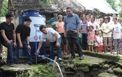<p><strong>SOLAR-POWERED WATER SUPPLY.</strong> Third District Representative Alfredo Benitez (3<sup>rd</sup> from left) opens the faucet of the reservoir tank during the turn-over rites and ceremonial launch of the solar-powered water supply system in Barangay Caliban, Murcia, Negros Occidental, with Mayor Andrew Montelibano (left), DOST-6 Regional Director Rowen Gelonga (2<sup>nd</sup> from left), TUP-Visayas campus director Eric Malooy (right), barangay and purok officials, and the beneficiaries. <em>(Contributed photo)</em></p>