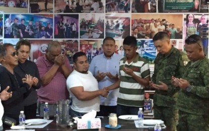 <p><strong>PEACE PACT.</strong> Erstwhile enemies Bong Abdul, 33 (white shirt), and Kindaw Samama, 45 (striped shirt), shake hands after signing the peace covenant on Sunday (Aug. 12) as Maguindanao Assemblyman Khadafy Mangudadatu (behind them) and other local and military officials join the community prayer. <em><strong>(Photo courtesy of 33rd IB)</strong></em></p>