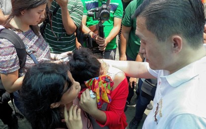 <p>Special Assistant to the President (SAP) Secretary Christopher Lawrence "Bong" Go comforts a crying teener whose face was swelling due to infection, during the Bancarera event at Time Beach in Davao City on Saturday (Aug. 18, 2018). Go immediately sent her to the hospital for medical attention. (Photo by Lilian C. Mellejor/PNA)</p>