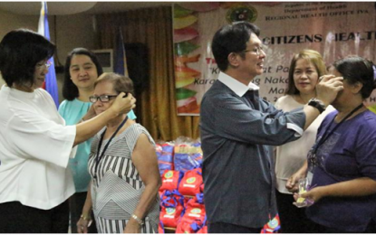 <p><strong>ELDERLIES</strong>. Opthalmologist Dr. Rubi T. Lim (left), and Department of Health (DOH) Calabarzon Regional Director Dr. Eduardo C. Janairo (right) put on the free eyeglasses to selected senior citizens during the Senior Citizen's Health Summit held in Pasay City on Sept. 27 to 28, 2018.<em> (Photo courtesy of DOH-4A)</em></p>