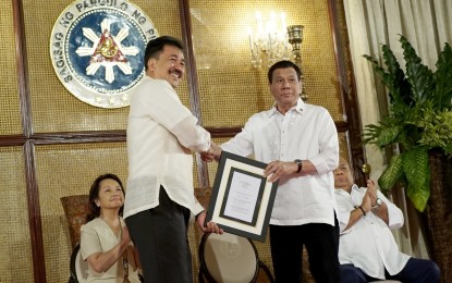 <p>President Rodrigo Roa Duterte receives the copy of the Republic Act 11079 or “An Act Mandating the Integration of the Maasin City College into the Southern Leyte State University” from Commission on Higher Education Commissioner Prospero de Vera during a ceremony at the Malacañan Palace on Tuesday (Oct. 9, 2018). Also in the photo are House Speaker Gloria Arroyo and Executive Secretary Salvador Medialdea. <em>(King Rodriguez/Presidential Photo)</em></p>