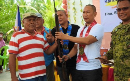 <p><strong>SURRENDER.</strong> Bangsamoro Islamic Freedom Fighters sub-commander Lapu-Lapu (in striped shirt) hands over his rifle to Maguindanao Governor Esmael Mangudadatu during Wednesday’s (Oct. 10, 2018) surrender rites in Barangay Midconding, General Salipada K. Pendatun, Maguindanao. Looking on is Lt. Colonel Harold Cabunoc (right), Army’s 33rd Infantry Battalion chief <em><strong>(Photo courtesy of 33rd IB)</strong></em></p>