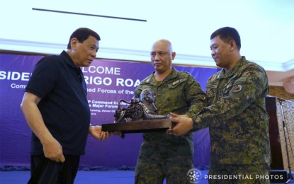 <p>President Rodrigo R. Duterte receives a token from incoming Army commander Brigadier General Macairog Alberto (middle) and Eastern Mindanao Command Commander Lieutenant General Benjamin Madrigal. <em>(File photo/PPD)</em></p>