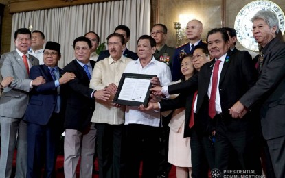 <p>President Rodrigo Duterte poses for a photo with legislators and negotiators in the peace process with the Moro Islamic Liberation Front (MILF), as well as top officials from the Armed Forces of the Philippines and Philippine National Police, during the presentation of the Bangsamoro Organic Law (BOL) to the MILF at Malacañan Palace on Aug. 6, 2018. <em>(Presidential photo)</em></p>