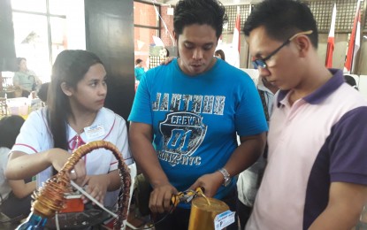 <p>Richard Cruz and Roger Manilhig Jr., teachers at Concepcion Technical-Vocational School, show Senior High School student Rizalyn Busico the basics of electrical wire manipulation for lampshades. </p>