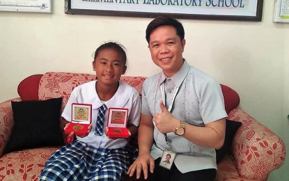 <p><strong>DOUBLES CHAMPION.</strong> <br />Marielle Alexi Jarata presents her medals to Don Mariano Marcos Memorial State University (DMMMSU) College of Education Elementary Laboratory School principal Rodelio de Vera Indong during a courtesy call on Nov. 6, 2018. Jarata won the doubles title and finished third in the singles category in the ATF Junior 14-Under Championships, which was held from Oct. 29 to Nov. 3 in Singapore. <em>(Contributed Photo)</em></p>