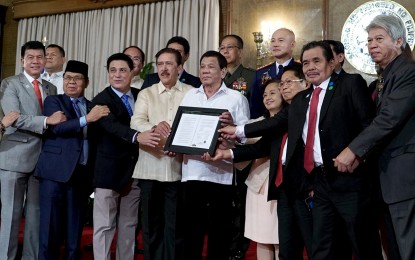<p>President Rodrigo R. Duterte poses for a photo with the legislators and negotiators in the peace process with the Moro Islamic Liberation Front (MILF), as well as top officials from the Armed Forces of the Philippines and Philippine National Police during the presentation of the Bangsamoro Organic Law (BOL) to the MILF at Malacañan Palace on Aug. 6, 2018. (<em>King Rodriguez/ Presidential Photo)</em></p>