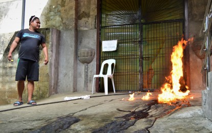 <p>A church volunteer sets on fire the clot of blood of the couple who died after the husband shot his wife before committing suicide at the side entrance of San Roque Parish church in Barangay Poblacion, Catarman, Camiguin on Sunday (Jan. 6. 2019).<em> (Photo by Jigger J. Jerusalem)</em></p>