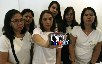 <p><strong>APPEAL FOR HELP.</strong> Crystal Allera (holding mobile phone), wife of 2nd Officer Claro Allera shows the photo of his husband and other sailors who are detained in Libya, during a press conference in Malate, Manila on Tuesday (Jan. 15, 2019). Allera and six other Filipino sailors were aboard the MT Levante, which was seized by the Libyan Coast Guard on suspicion of oil smuggling in August 2017. <em>(PNA photo by Joey Razon)</em></p>