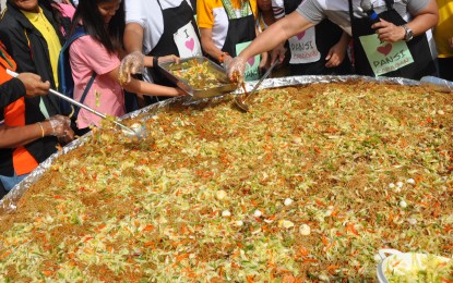 <div><strong>GIANT PANSIT.</strong> Townsfolk partake of Pansi Cabagan, a popular rice noodle dish in the town, served on a giant <em>bilao</em> during the Pansi Festival opening on January 23, 2019. <em>(Photo by Villamor Visaya Jr.)</em></div>