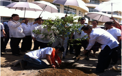 <p>Department of Environment and Natural Resources (DENR) Secretary Roy A. Cimatu shovels earth into the newly planted “almaciga” sampling at the front elevated landscaped area of the new DENR Region 4A (Calabarzon) office building (background) during the inauguration ceremony of its new home next to the Mayapa-Canlubang interchange exit in Columba City on Jan. 25, 2019. <strong><em>(Photo by Saul E. Pa-a)</em></strong></p>