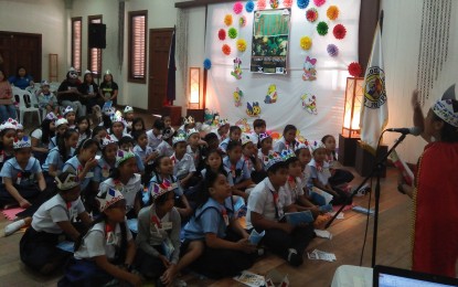 <p>Pupils from Montes I Elementary School listen to Janamay Calibre as she delivers a story during the World Read Aloud Day held at the Ker and Company Bldg, in this city, Friday (Feb. 1, 2019). </p>