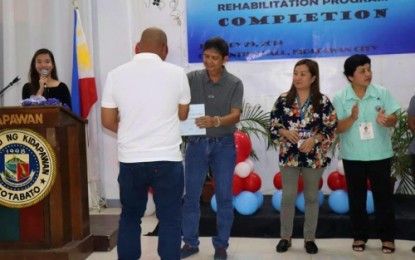<p>A PWUD receives his certificate from Kidapawan City Mayor Joseph Evangelista as other local officials look on during Friday's graduation here. <em><strong>(Kidapawan CIO)</strong></em></p>