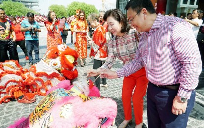 <p>DOTTING THE DRAGON’S HORN.  Duty Free Philippines Corporation (DFPC) Chief Operating Officer Vicente Pelagio A. Angala (right) and Maria Salome P. Angala (in red pants), Area Business Head of Metrobank dot the dragon’s horn as part of the Chinese New Year celebration held in front of the upscale DFPC Luxe Duty Free Store at SM Mall of Asia Complex in Pasay City on Tuesday (Feb. 5, 2019). Angala said DFPC is currently focused on Chinese tourists although they are now planning to partner with other foreign posts in Manila. <em>(PNA photo by Ben Briones)</em></p>