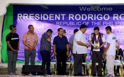 <p><strong>LAND AWARDS.</strong> President Rodrigo Duterte (second from right in waist coat) hands over a Certificate of Land Ownership Award to one of the agrarian reform awardees during the distribution of land titles to 780 beneficiaries in Buluan, Maguindanao, on Monday (Feb. 11). Looking on is Department of Agrarian Reform Secretary John Castriciones (3rd from right). <em>(Photo by PNA Cotabato)</em></p>