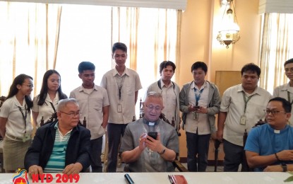 <p><strong>NATIONAL YOUTH DAY.</strong> Cebu Archbishop Jose Palma (center) tries the National Youth Day 2019 mobile applications "Kaabay" and "Pedro's Journey" in his smartphone during the launching and memorandum of agreement signing at the Filipiñana Hall, Archbishop's Residence, Cebu City on March 5, 2019. With him are <span class="s1">University of San Carlos president, Rev. Fr. Dionisio Miranda (left), </span><span class="s1">Cebu Diocesan Youth Director Rev. Fr. Mark Barneso (riht), and students of USC. <em>(Photo courtesy of NYD 2019 - Cebu Facebook page)</em></span></p>