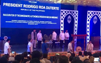 <p><strong>BARMM INAUGURATION. </strong>President Rodrigo Duterte (foreground, second from right) bangs the “agong” marking the investiture of the Bangsamoro Autonomous Region in Muslim Mindanao (BARMM) as its interim chief minister Ahod Ebrahim (right), looks on during a ceremony held Friday (March 29, 2019) in Cotabato City. The Chief Executive reiterated his commitment to work for the benefit of the Moro people in the country until the end of his term in 2022. <em>(Photo by PNA Cotabato)</em></p>