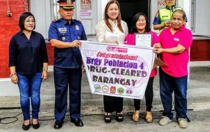 <p><strong>DRUG-CLEARED. </strong>Police Maj. Resty Soriano, Silang police chief, presents Barangay Poblacion IV to Mayor Omil Poblete as one of 10 drug-cleared villages in the town during a simple rite on Monday (April 29, 2019) at the town plaza. <em>(Photo by Dennis Abrina)</em></p>