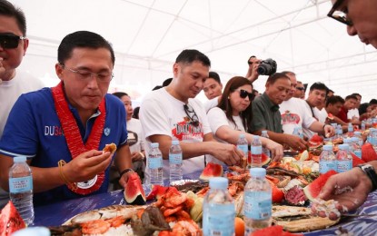 <p><strong>DULANG. </strong>Former Special Assistant to the President Christopher "Bong" Go (second from left), Pangasinan Governor Amado Espino III (third from left), and other provincial officials share the feast at the Dulang (long table) boodle fight during the Pista'y Dayat commemorative program on May 1 at Lingayen Pangasinan. <em>(Photo courtesy of Provincial Government of Pangasinan's facebook page) </em></p>