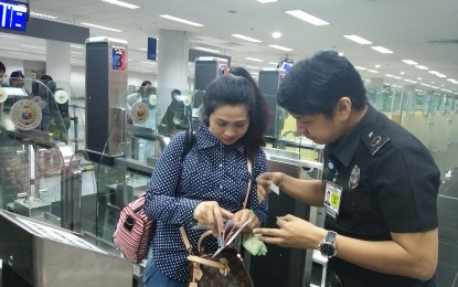 <p><span style="color: #000000;">Immigration Port Operations Division chief, </span><span style="color: #000000;">Grifton Medina, assists a passenger in NAIA Terminal 3. <em>(File photo by Cristina Arayata)</em></span></p>