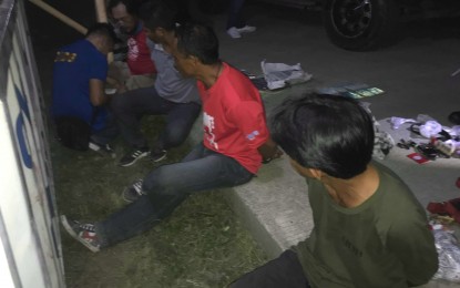 <p><strong>NABBED FOR GUNS.</strong> The five arrested people sitting on the roadside pavement at the police checkpoint along Km. 80 in Sulop, Davao del Sur while being processed by a personnel of the Criminal Investigation and Detection group (CIDG).  The suspects were arrested Friday night (May 10, 2019). (<em>Photo courtesy of  CIDG-11)</em></p>