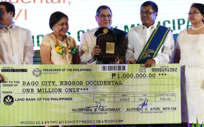<p><strong>PRODUCTIVE.</strong> Bago City Mayor Nicholas Yulo (center),  City Agriculturist Carlito Indencia (2<sup>nd</sup> from right), and DA-Western Visayas Regional Executive Director Remelyn Recoter (right) receive the trophy and the symbolic check for PHP1 million from Senator Cynthia Villar (2nd from left) and other officials during the 2018 Rice Achievers Awards held at the Philippine International Convention Center in Pasay City on Thursday (May 30, 2018).  The southern Negros city’s average yield per hectare increased from 4.3 metric tons in 2017 to 4.45 metric tons in 2018. <em>(Photo courtesy of Department of Agriculture Regional Field Unit-6)</em></p>