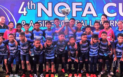 <p><strong>CHAMPIONS.</strong> The Under 13 booters of Dynamic FC, champions of the Negros Occidental Football Association Cup 2019, with NOFA  president Ricardo Yanson Jr. (left), tournament chairperson Angelica Jochico (2<sup>nd</sup> row, right), and PFF Youth Development head Reiji Hirata during the awards ceremony on Sunday. The host team defeated LGU Barotac Nuevo of Iloilo, 5-nil, to win this year’s title. <em>(Photo courtesy of Archie Rey Alipalo)</em></p>