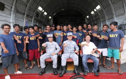 <p><strong>RESCUED</strong>. Philippine Navy Capt. Alex Guianan (seated left), Commodore Antonio Palces (seated center) and Bureau of Fisheries and Aquatic Resources (BFAR) Regional Director Eleazar Salilig (seated right) do the signature fist pose with fishermen of the F/B Gem-Ver shortly after a turnover ceremony at the BRP Ramon Alcaraz on Friday (June 14, 2019). The fishermen were rescued by a Vietnamese vessel after their boat capsized when it was allegedly hit by a Chinese fishing vessel off Recto Bank on June 9. <em>(PNA photo by Joey O. Razon)</em></p>