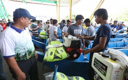 <p><strong>LIVELIHOOD PACKAGE.</strong> Agriculture Secretary Emmanuel Piñol turns over fishing boats to each of the 22 Filipino fishermen affected by the Recto Bank incident at the town plaza of San Jose, Occidental Mindoro on Wednesday (June 19, 2019). The fishermen each received a sack of rice and a soft loan amounting to PHP25,000 payable in three years with no interest. <em>(PNA photo by Oliver Marquez)</em></p>