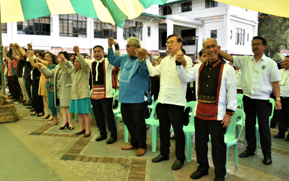 <p><strong>NEW BAGUIO OFFICIALS. </strong>New local officials of the Baguio City government while hold hands while singing 'If We Hold On Together' during the flag-raising ceremony at the City Hall on Monday (July 1, 2019). This marks the first day of work of the new set of officials after their election in May. <em>(Photo courtesy: Redjie Melvic Cawis/PIA-CAR)</em></p>