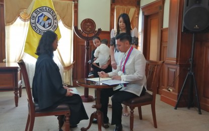 <p><strong>NEW SP PRESIDING OFFICER. </strong>Pangasinan Vice Governor Mark Lambino (right) signs his oath of office as his wife Lani, a lawyer, looks on when he was sworn into office by Regional Trial Court Judge Maria Laarni Parayno (left) last June 30, 2019. The vice governor is the son of Secretary Raul Lambino, administrator of the Cagayan Economic Zone Authority and Mangaldan Mayor Marilyn Lambino.  (<em>Photo by Liwayway Yparraguirre) </em></p>