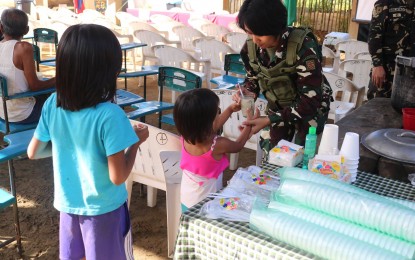<p><strong>COMMUNITY SUPPORT PROGRAM.</strong> A female soldier serves food to children during the conduct of a community support program in an upland village in Lope de Vega, Northern Samar. The activity aims to facilitate the government’s development programs with the army hearing issues and concerns of villagers and bringing them to the attention of concerned government offices. <em>(Photo courtesy of Army 43rd Infantry Batallion)</em></p>