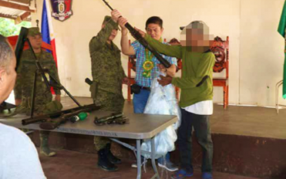 <p><strong>SURRENDERER.</strong> One of five members of the Bangsamoro Islamic Freedom Fighters (right) hands over his rifle to Col. Jose Narciso (2nd from left), who is assisted by Talitay Mayor Allan Sabal (3rd from left),  during a turnover ceremony in Datu Anggal Midtimbang, Maguindanao on Thursday (July 18, 2019). The five surrenderers also received livelihood and housing assistance to help them start a new life. <em>(Photo courtesy of 6th ID)</em></p>