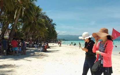 <p>Tourists walk along White Beach in Boracay<em> (File photo)</em></p>