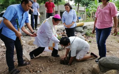 <p><strong>BREAKING GROUND.</strong> Dumaguete Bishop Julito Cortes, D.D. plants a tree as he leads the simple groundbreaking rites for a drug rehabilitation center in Silab, Amlan in Negros Oriental on Saturday (July 27, 2019). The facility is a collaboration between the diocese and the Fazenda da Esperança or The Farm of Hope, which has a rehabilitation center in Masbate. <em>(Photo by Judy Flores Partlow)</em></p>