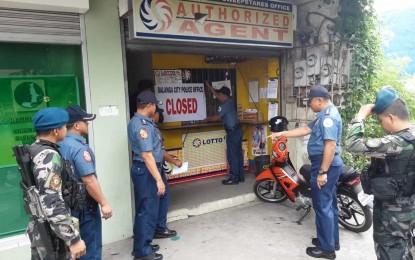 <p><strong>LOTTO CLOSED</strong>. Police personnel post a "closed sign" in one of the lotto outlets in Balanga City, Bataan on Saturday (July 27, 2019). The move is in adherence to President Rodrigo Duterte's order on the crackdown of state-accredited gambling. <em>(Photo courtesy of the Police Regional Office 3)</em></p>