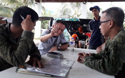 <p><strong>SEARCH AND RESCUE.</strong> Lt. Col. Jose Mari F. Torrenueva II, commander of the 91st Infantry Battalion, Philippine Army (right), discusses with Tito Dizon (center), father of student pilot Aaron Dizon, the search and rescue operations for the younger Dizon and the Cessna C-152 aircraft in Aurora province. Both the plane and the pilot are missing since Sunday.<em> (Photo by Jason de Asis)</em></p>