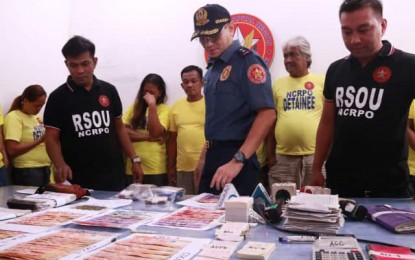 <p><strong>ANTI-GAMBLING OPERATION.</strong> NCRPO chief, Maj. Gen. Guillermo Eleazar examines illegal gambling paraphernalia confiscated from 12 bet collectors he presented to the media at the NCRPO Headquarters in Camp Bagong Diwa in Taguig City on Sunday (Aug. 4, 2019).  Simultaneous operations against illegal gambling in Metro Manila has led to the arrest of the 12 suspects. <em>(Courtesy of NCRPO PIO)</em></p>