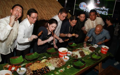 <p><strong>'EATS. MORE FUN IN THE PHILIPPINES'.</strong> Tourism Secretary Bernadette Romulo-Puyat (3rd from left) together with Jollibee Food Corporation officials lead by Ernesto Tanmantiong (2nd from left), indulge in the Filipino boodle feast during the DOT and Jollibee launch of "Eats. More Fun in the Philippines" at the Islas Pinas Food & Heritage Village, Double Dragon Plaza in Pasay City on Saturday (August 31, 2019). The campaign highlights the top dishes the country has to offer. <em>(PNA photo by Gil Calinga)</em></p>