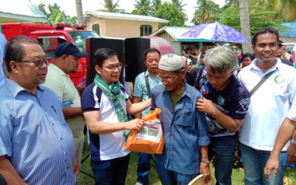 <p><strong>‘PROJECT TABANG’.</strong> Lawyer Naguib Sinarimbo (second left), interior minister of the Bangsamoro Autonomous Region in Muslim Mindanao, hands over a relief pack to one of the beneficiaries during an outreach mission under “Project Tabang” in Barangay Pidsandawan, Mamasapano, Maguindanao on Monday (Sept. 2, 2019). <em>(Photo courtesy of BPI-BARMM)</em></p>
