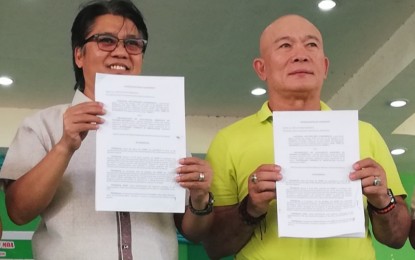 <p><strong>PARTNERSHIP.</strong> National Anti-Poverty Commission Secretary Noel Felongco (left) and Mayor Enrique Miravalles show their memorandum of agreement for the PHP3-million poverty alleviation project in Valladolid at the town covered court on Thursday (Sept. 26, 2019). Funded by the Philippine Amusement and Gaming Corporation (PAGCOR), Valladolid is one of the seven priority areas for the implementation of the prototype projects under the grant. <em>(PNA photo by Nanette L. Guadalquiver)</em></p>