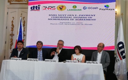 <p><strong>E-PAYMENT</strong>. Trade and Industry Secretary Ramon Lopez (center) says providing the public with the e-payments option is in line with President Rodrigo Duterte's mandate on the ease of doing business, during the signing of memorandum of agreement among the DTI, Landbank, Bureau of the Treasury, PayMaya and GCash on Friday (Sept. 27, 2019). Lopez said the DTI is working with the Department of Information and Communications Technology (DICT) in creating a single system that could fast-track business processes. (<em>PNA photo by Cristina Arayata) </em></p>